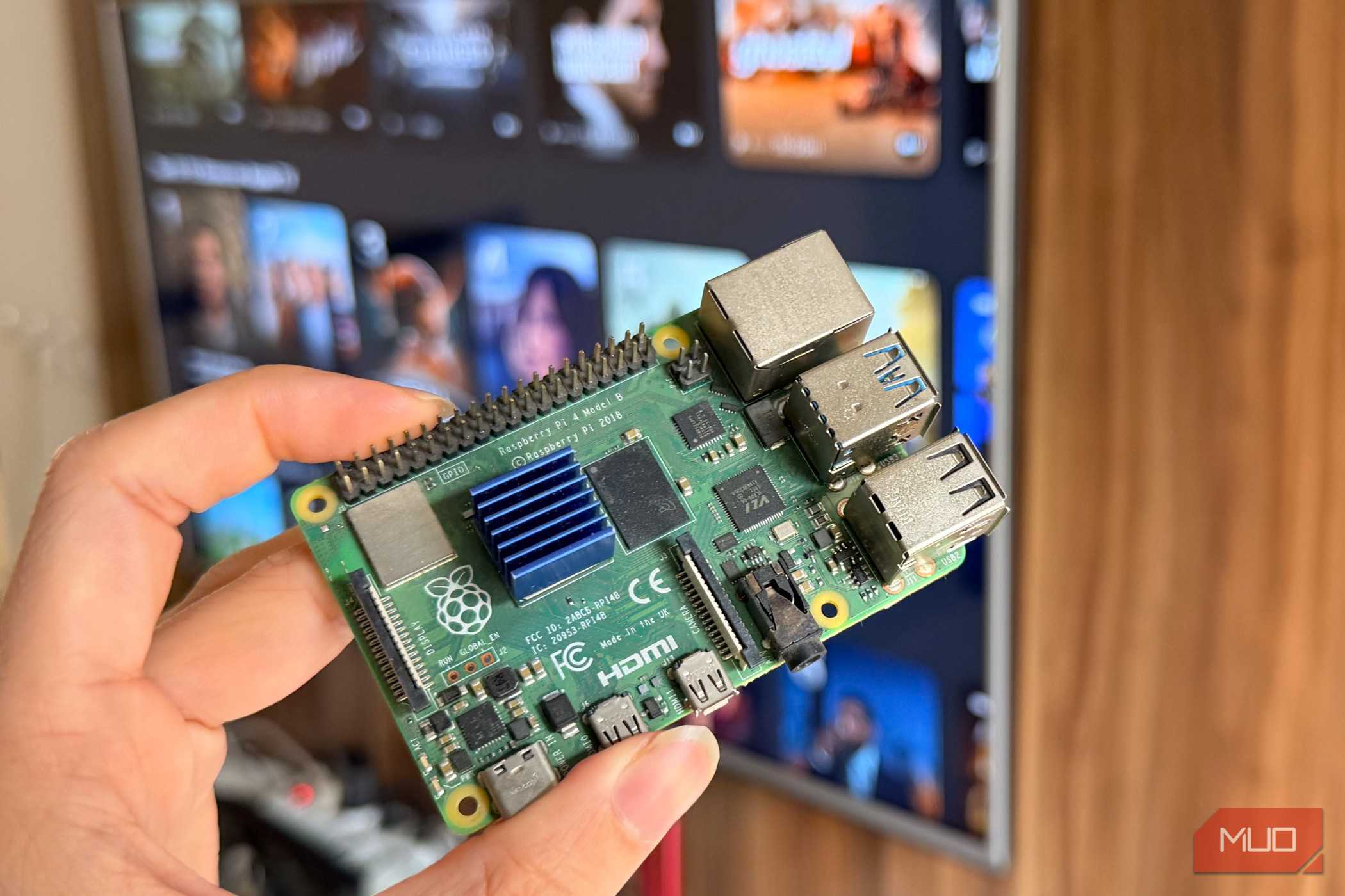 Hand holding a Raspberry Pi 4 in front of a smart TV
