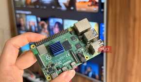Hand holding a Raspberry Pi 4 in front of a smart TV