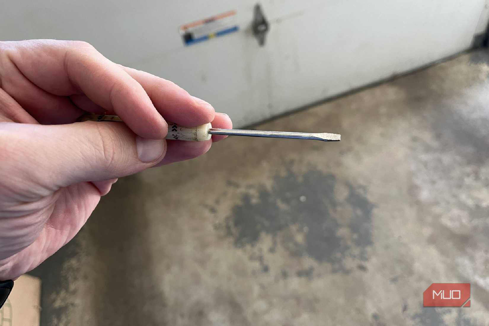 A thin flathead screwdrivrer being held