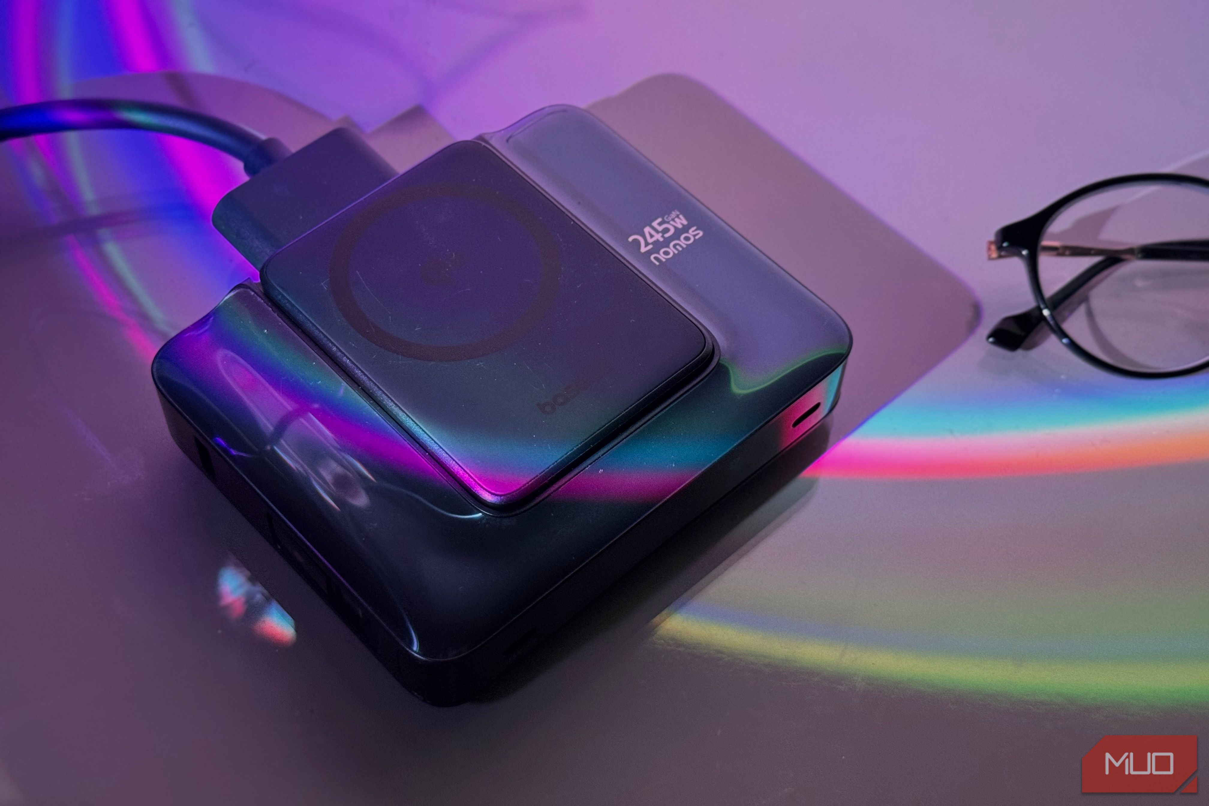wireless charging pad and power bank with colorful light refraction on purple background next to glasses