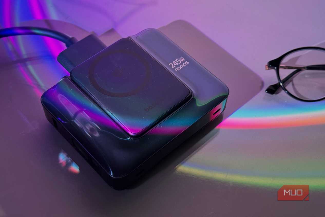 wireless charging pad and power bank with colorful light refraction on purple background next to glasses