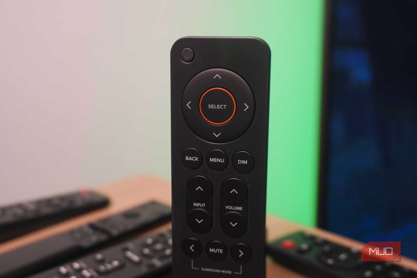 A standing remote with a pile of remotes in the background.