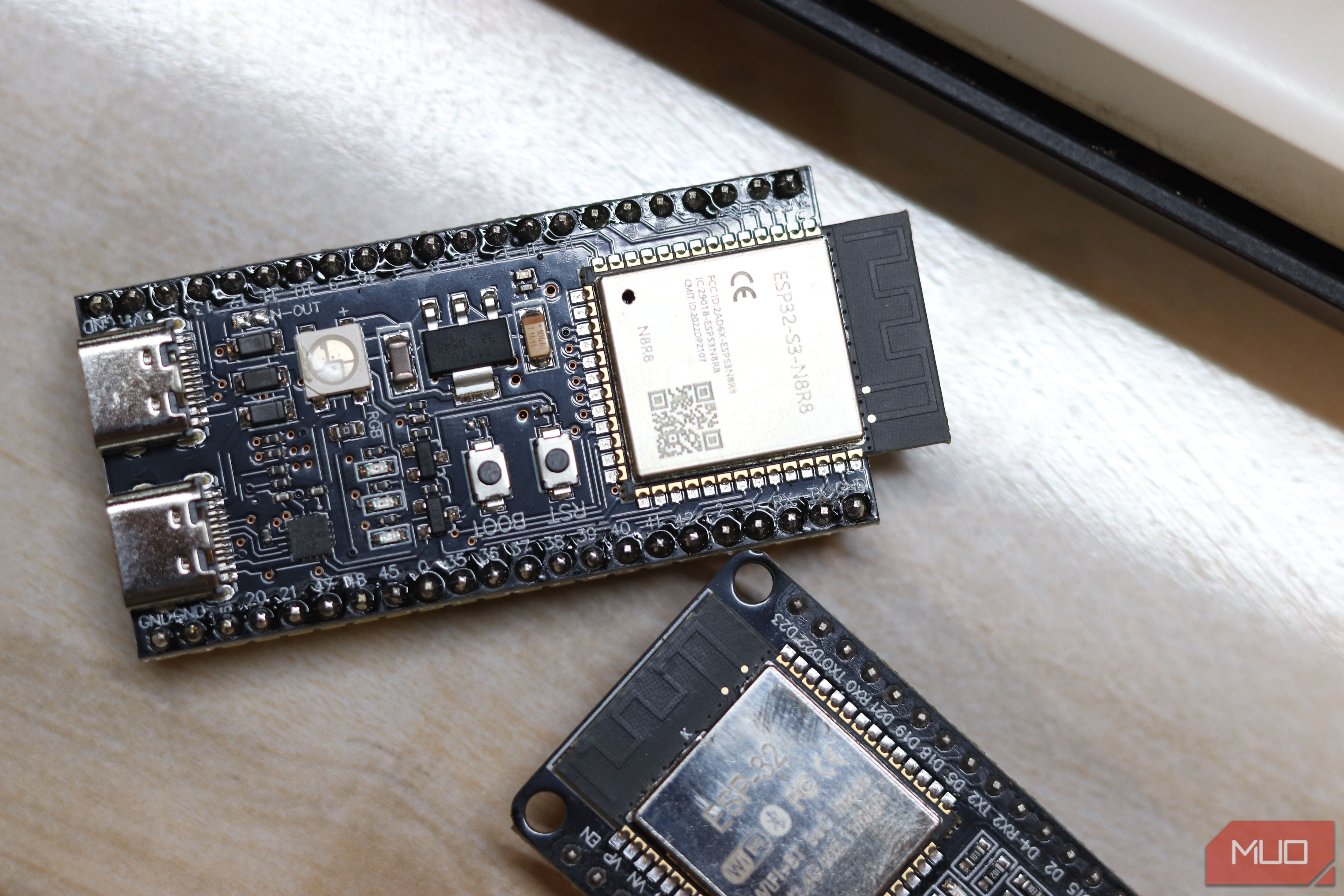 ESP32-S3 and ESP32 classic boards on a desk near a window