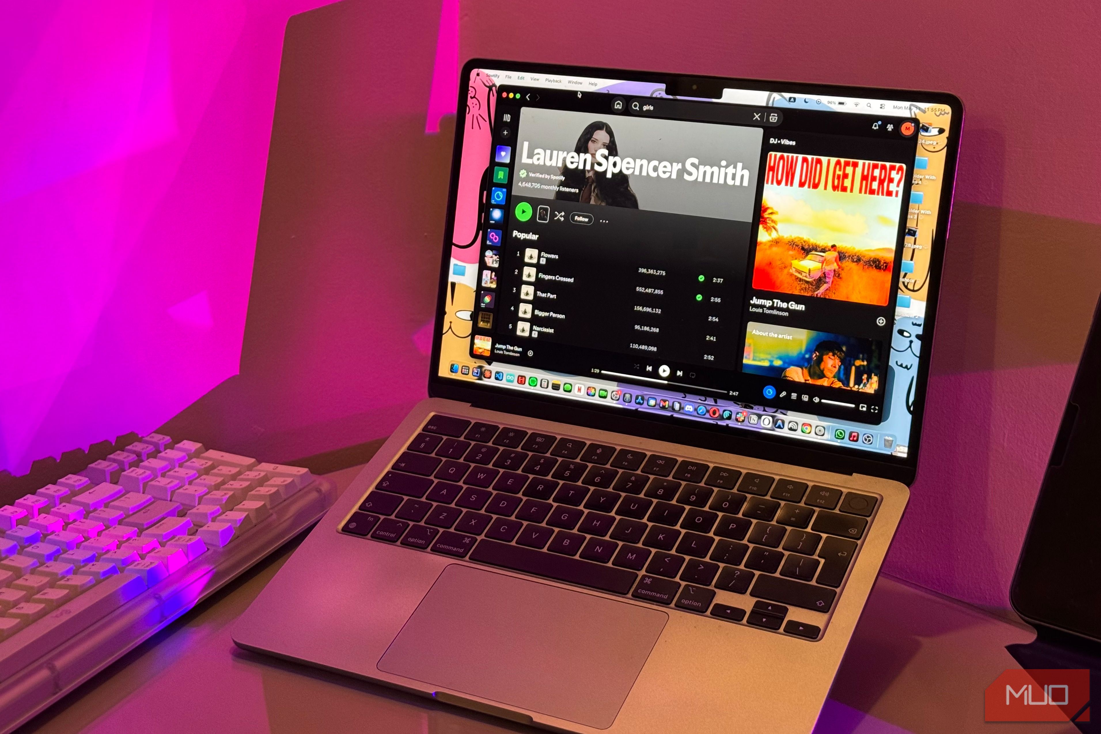 macbook laptop displaying discord app and youtube video with pink neon lighting in background