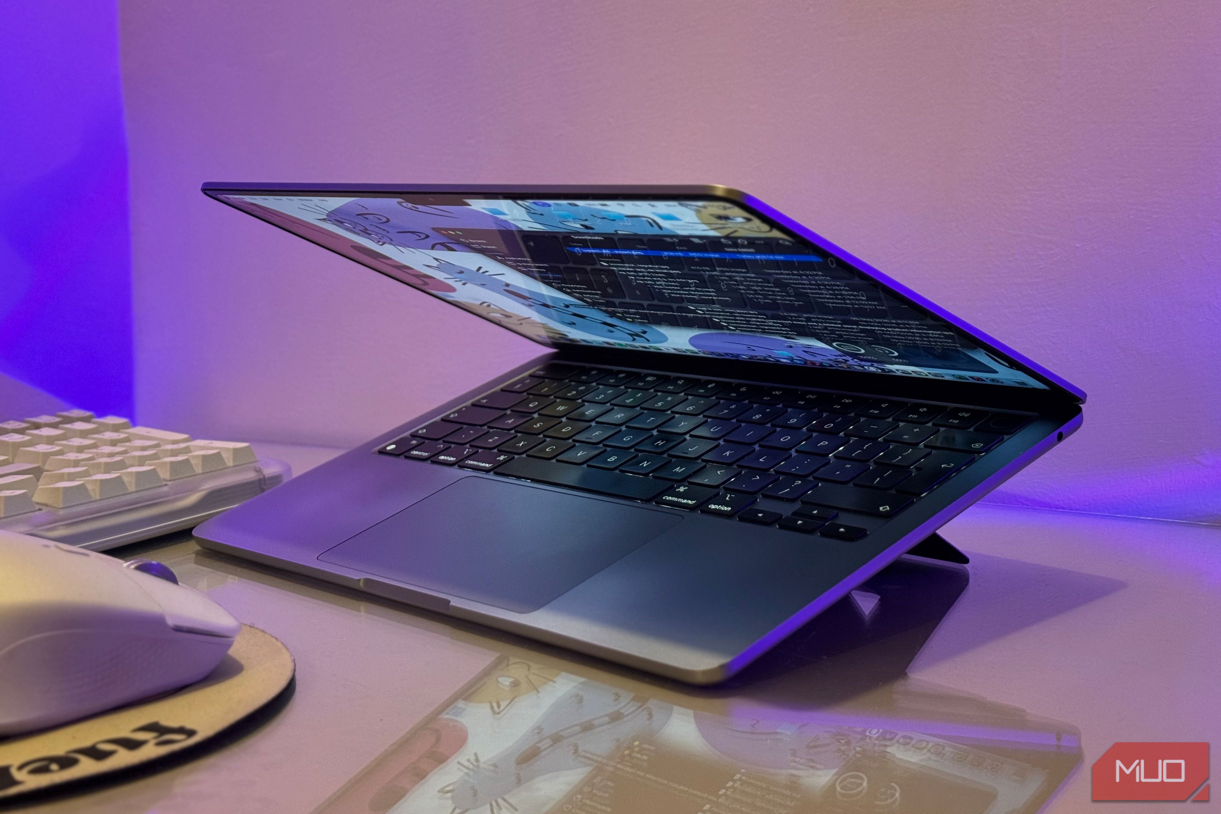 open laptop with blue screen display on purple lit desk with keyboard and mouse