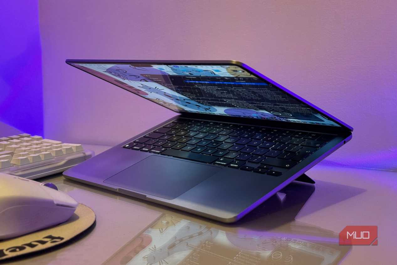 open laptop with blue screen display on purple lit desk with keyboard and mouse