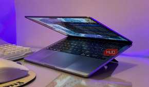 open laptop with blue screen display on purple lit desk with keyboard and mouse