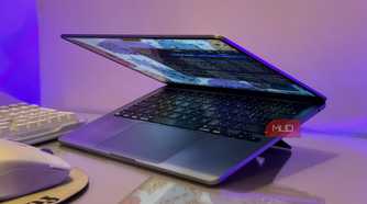 open laptop with blue screen display on purple lit desk with keyboard and mouse