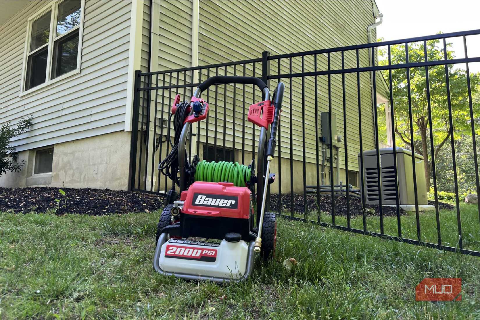 A Bauer 2000 PSI Power Washer in front of a dirty side of a house.