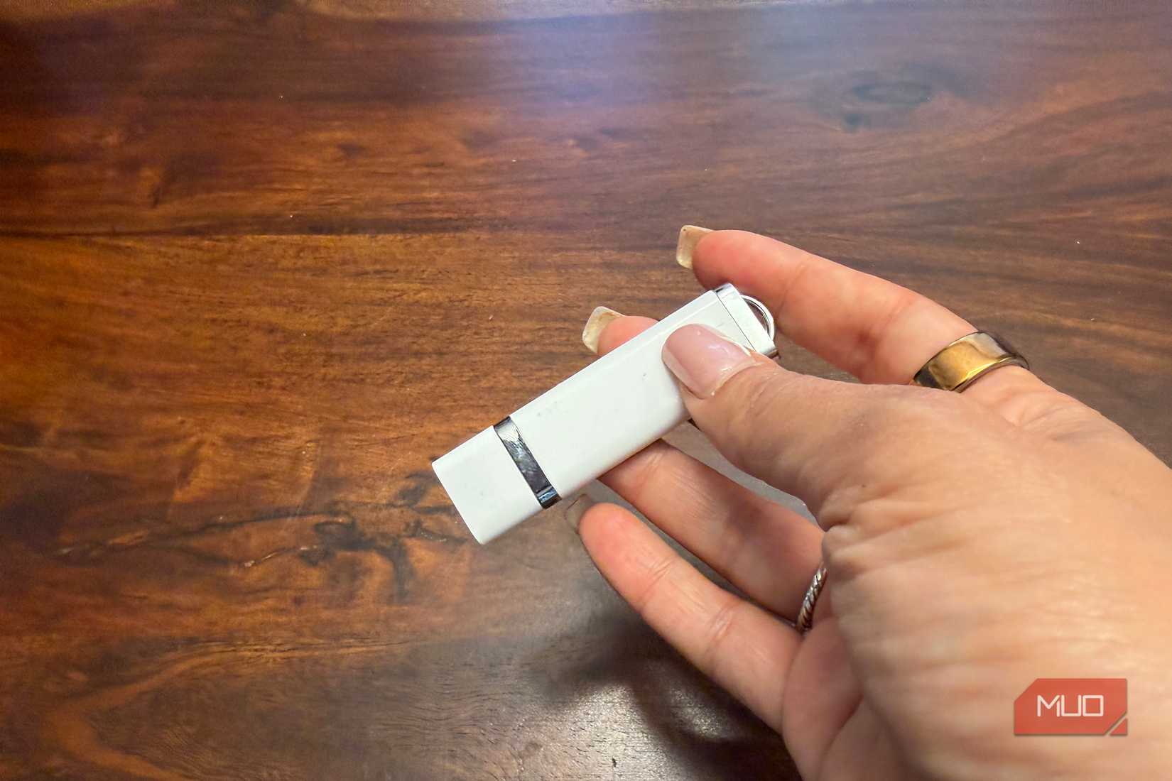 A white USB drive in hand with the cap on.