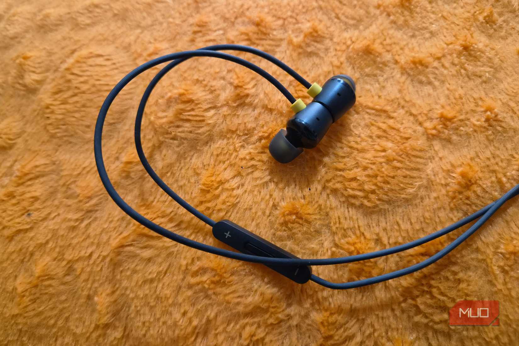 Wired earphones on an orange pillow