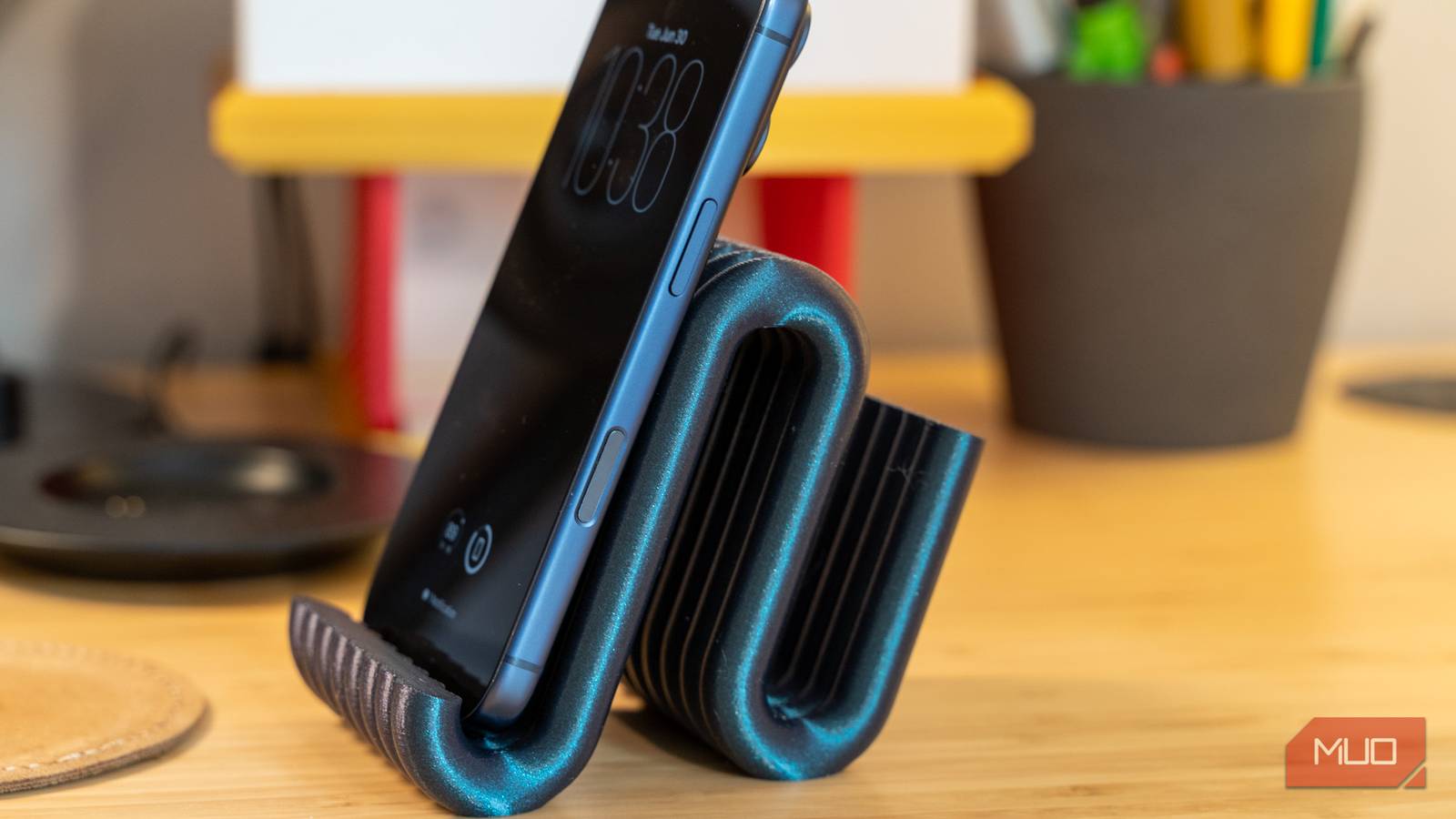 3D printed phone holder side angle with iPhone leaning in curved stand.