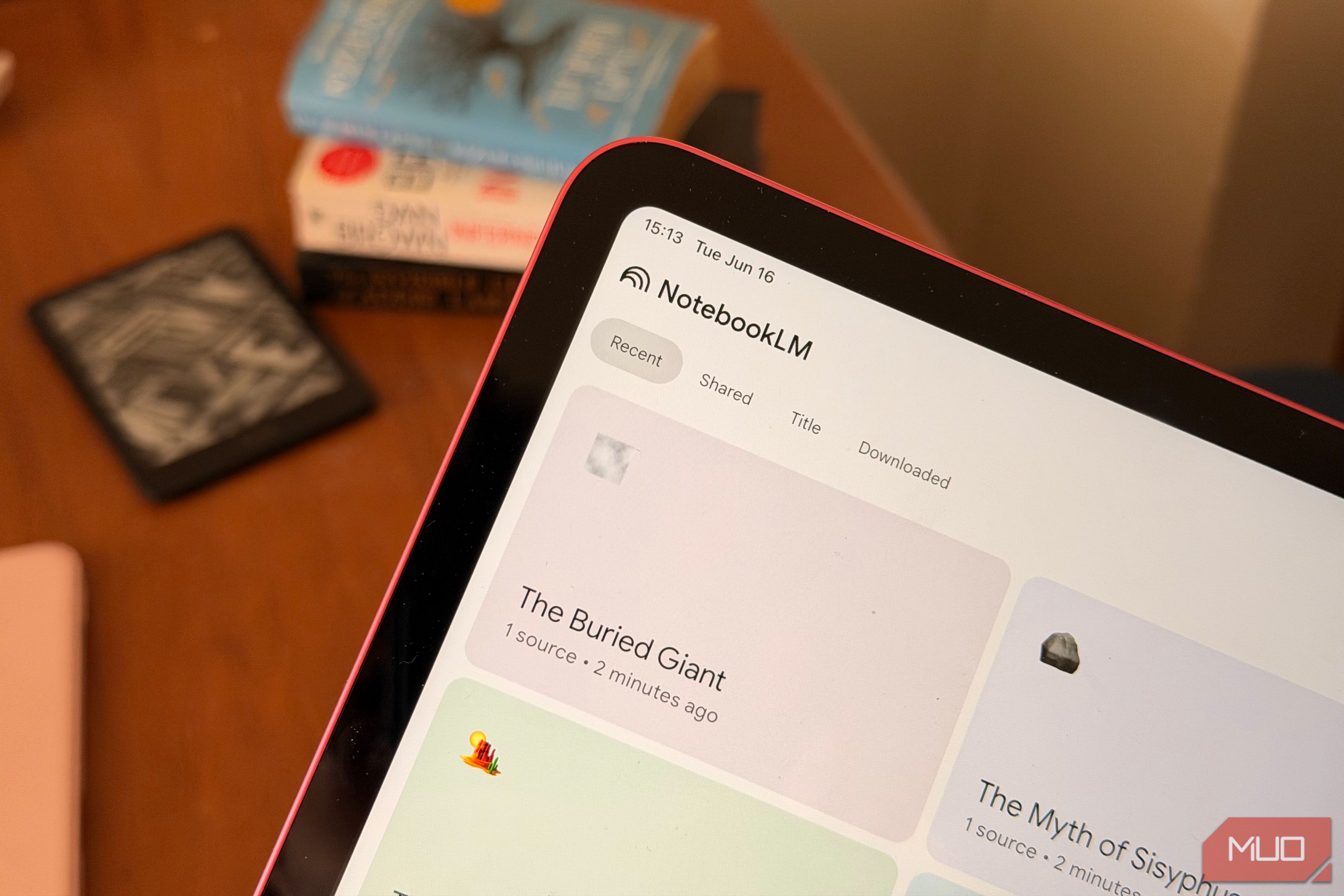 An iPad showing NotebookLM with books and a Kindle in the background