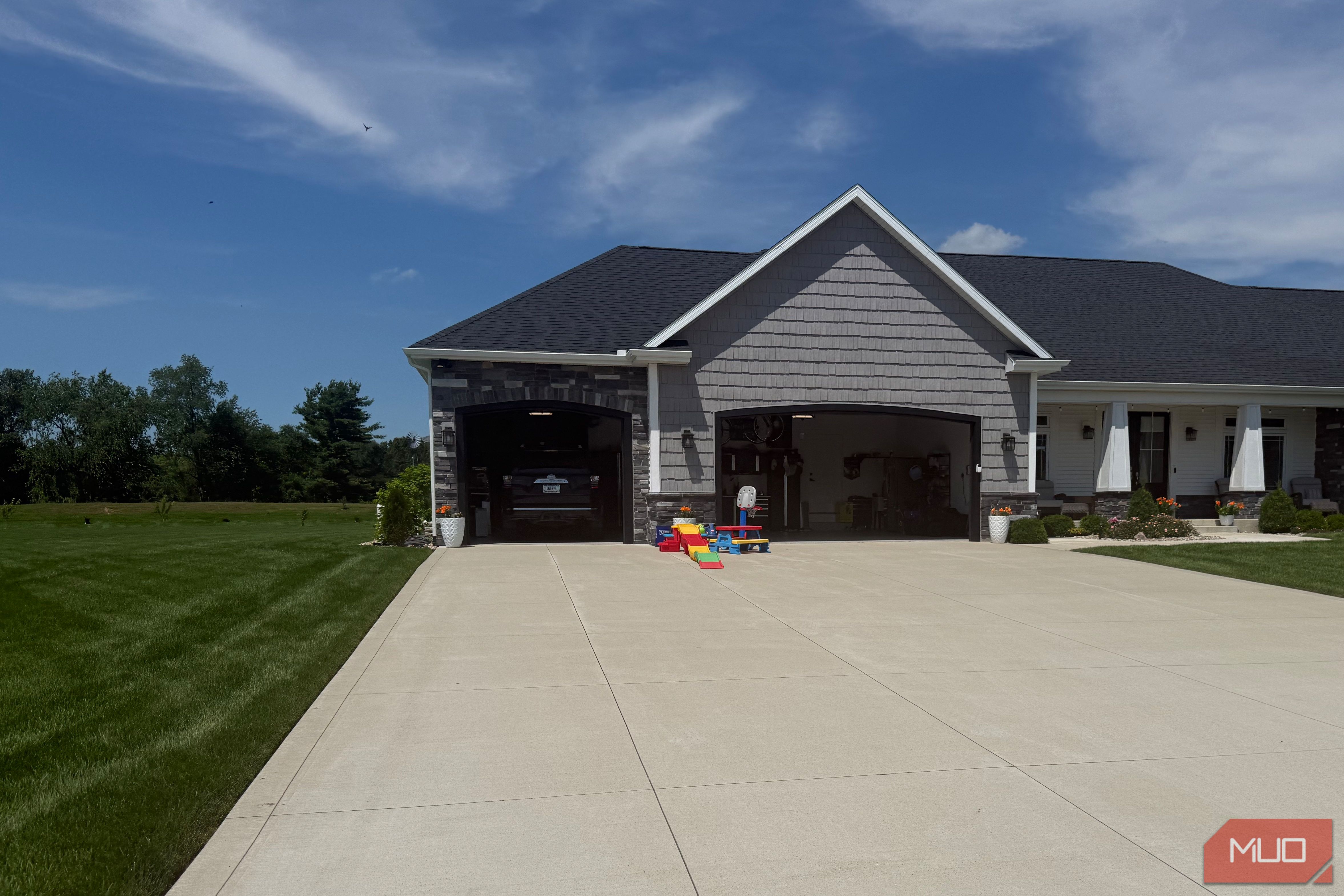 gray house exterior with two open garage doors and kids play toys