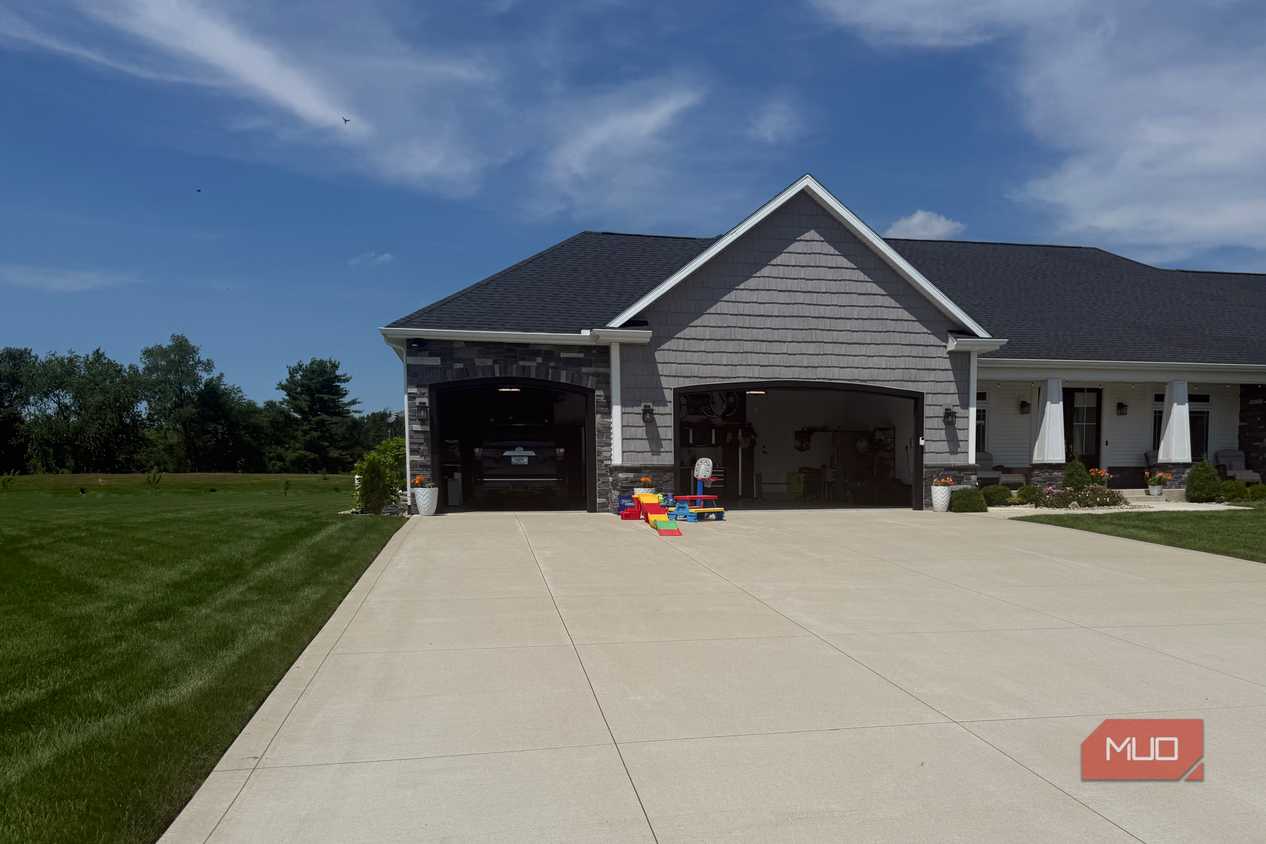gray house exterior with two open garage doors and kids play toys