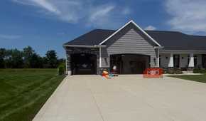 gray house exterior with two open garage doors and kids play toys