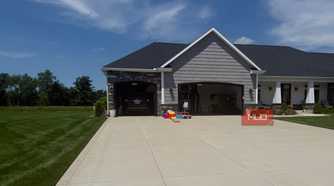 gray house exterior with two open garage doors and kids play toys
