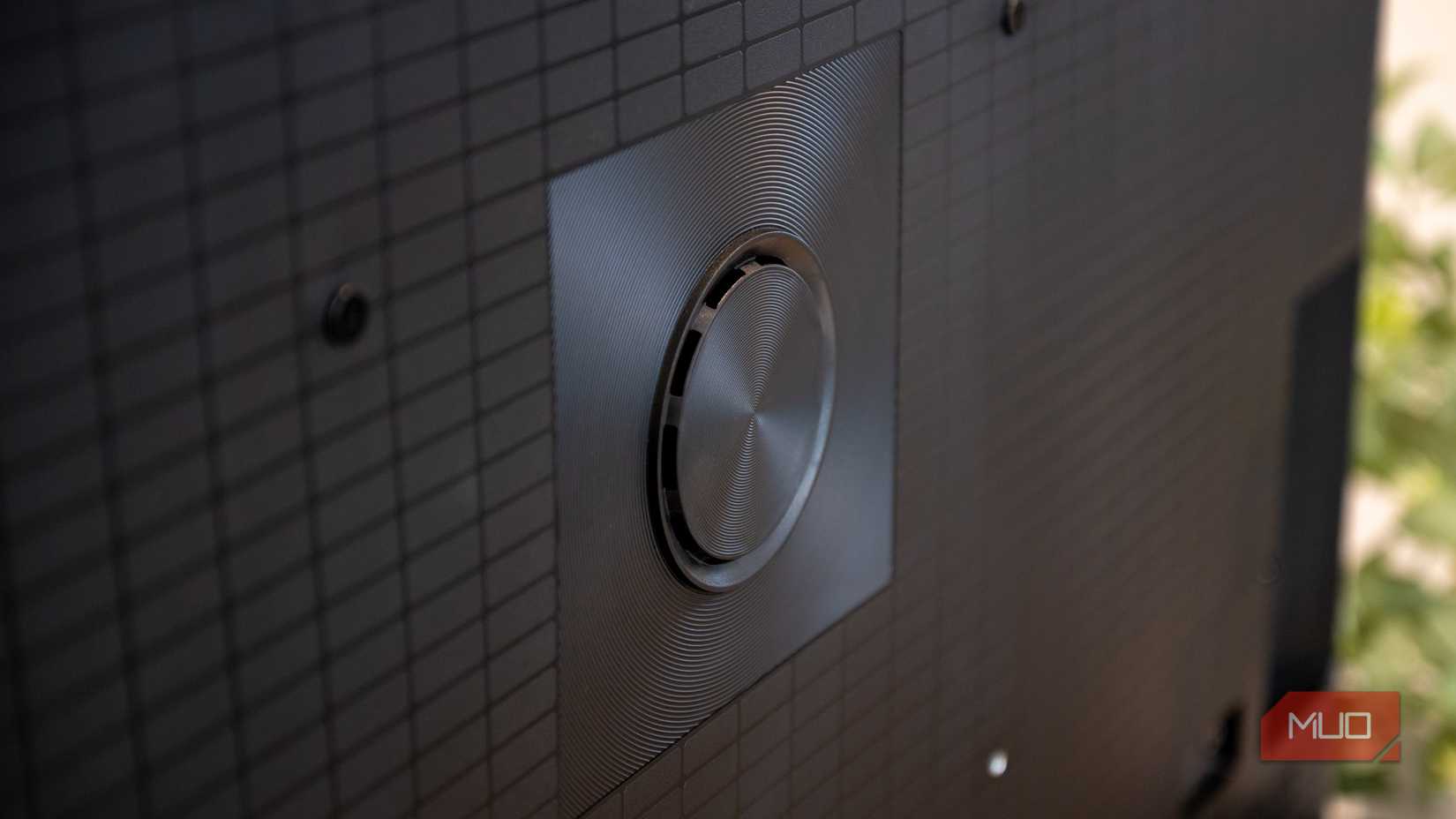 Close-up of the Hisense U6 Pro rear speaker driver centered on the textured grid back panel with mounting screws visible.