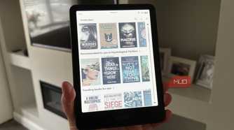 A Kindle Colorsoft held in-hand displaying a library of e-books