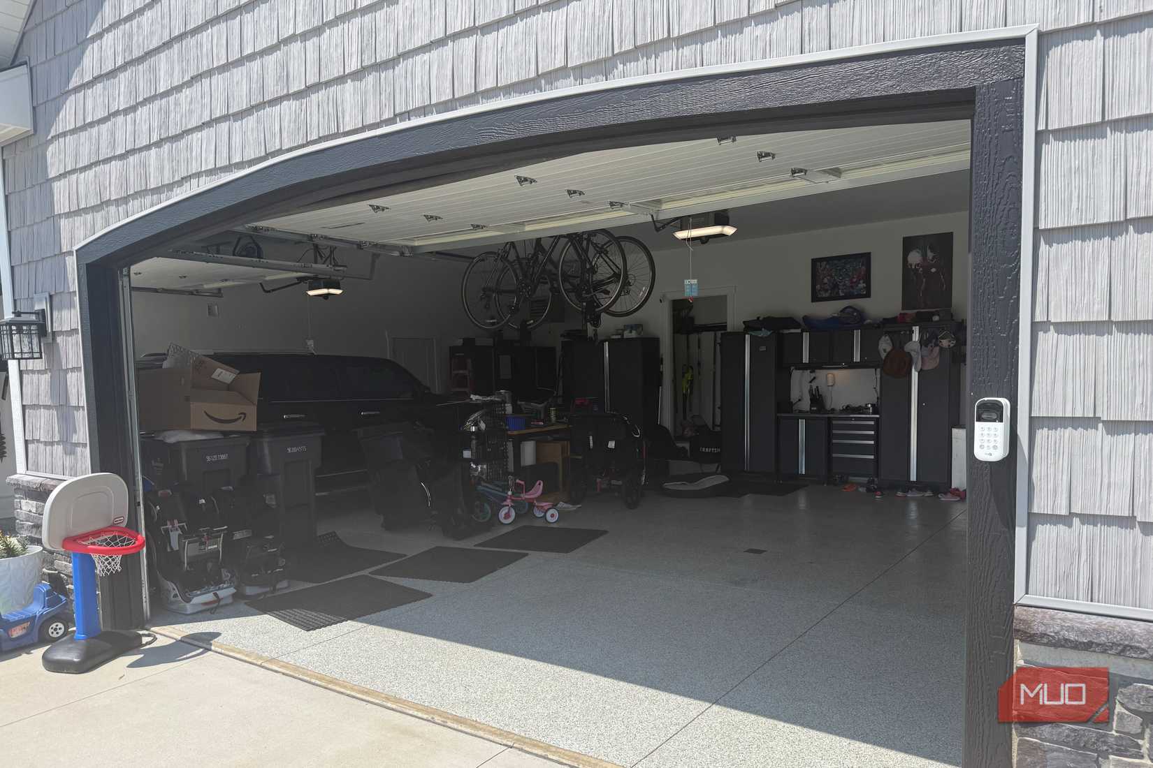 open garage with black suv hanging bikes and storage cabinets