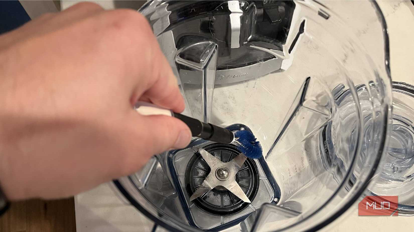 An OXO Good Grips appliance brush inside a blender cleaning the blades.