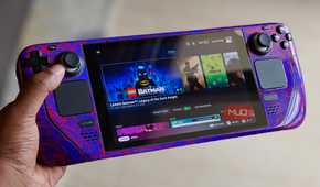 Hand holding a Steam Deck console showing LEGO Batman in Steam