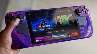 Hand holding a Steam Deck console showing LEGO Batman in Steam