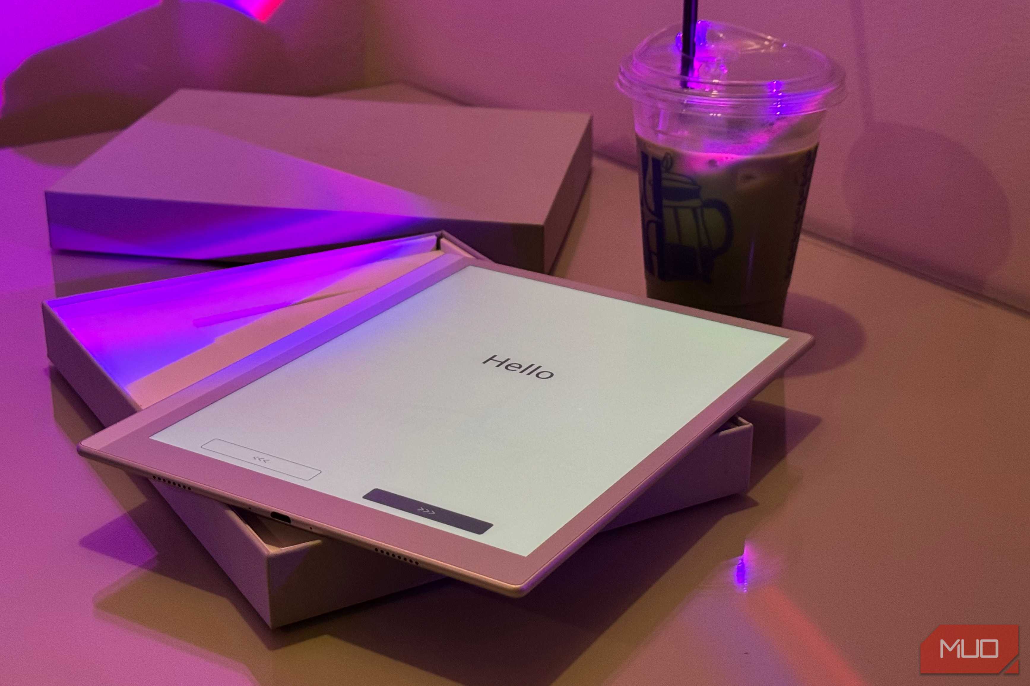 tablet displaying hello text on desk with purple lighting and beverage cup