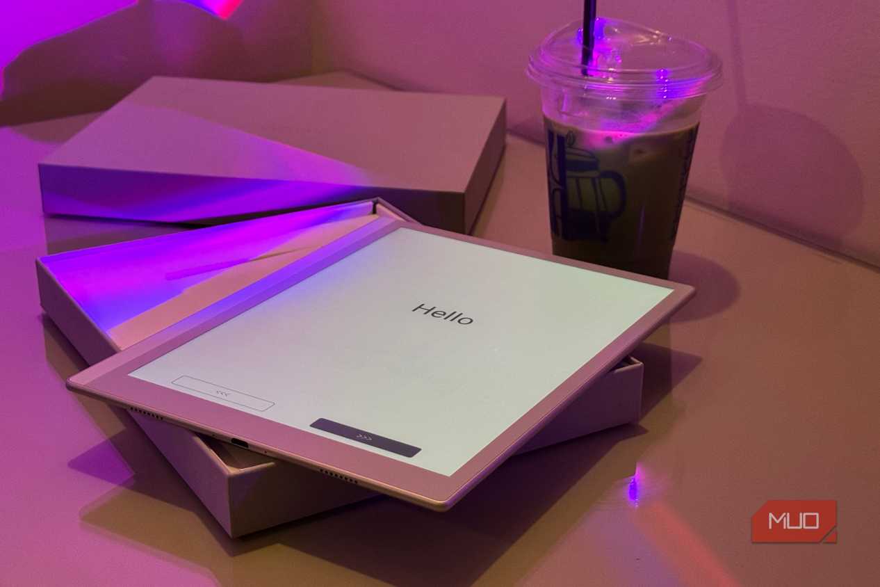 tablet displaying hello text on desk with purple lighting and beverage cup