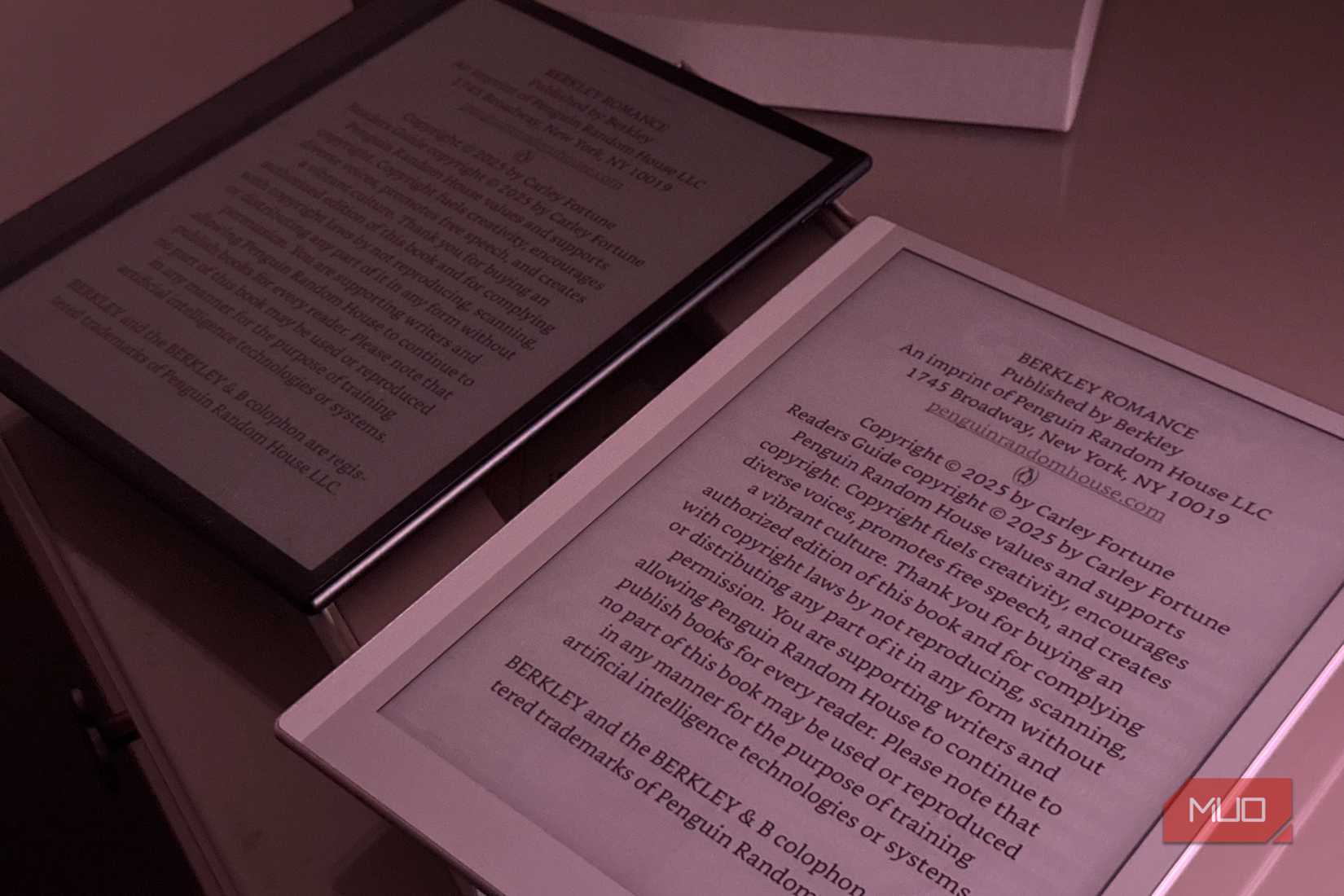 two e readers displaying text pages on a pink surface