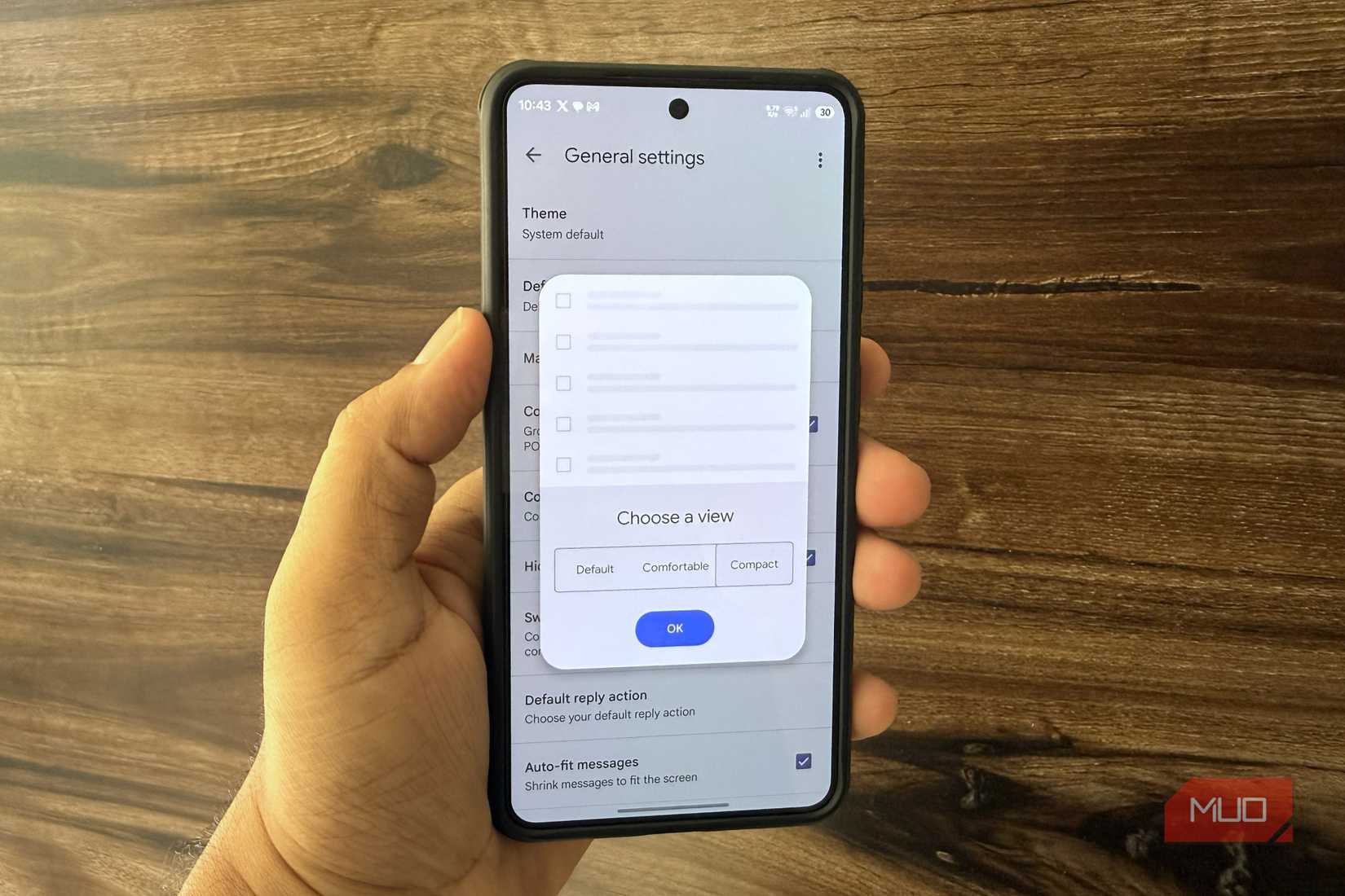 Android phone in hand showing Gmail email view settings menu