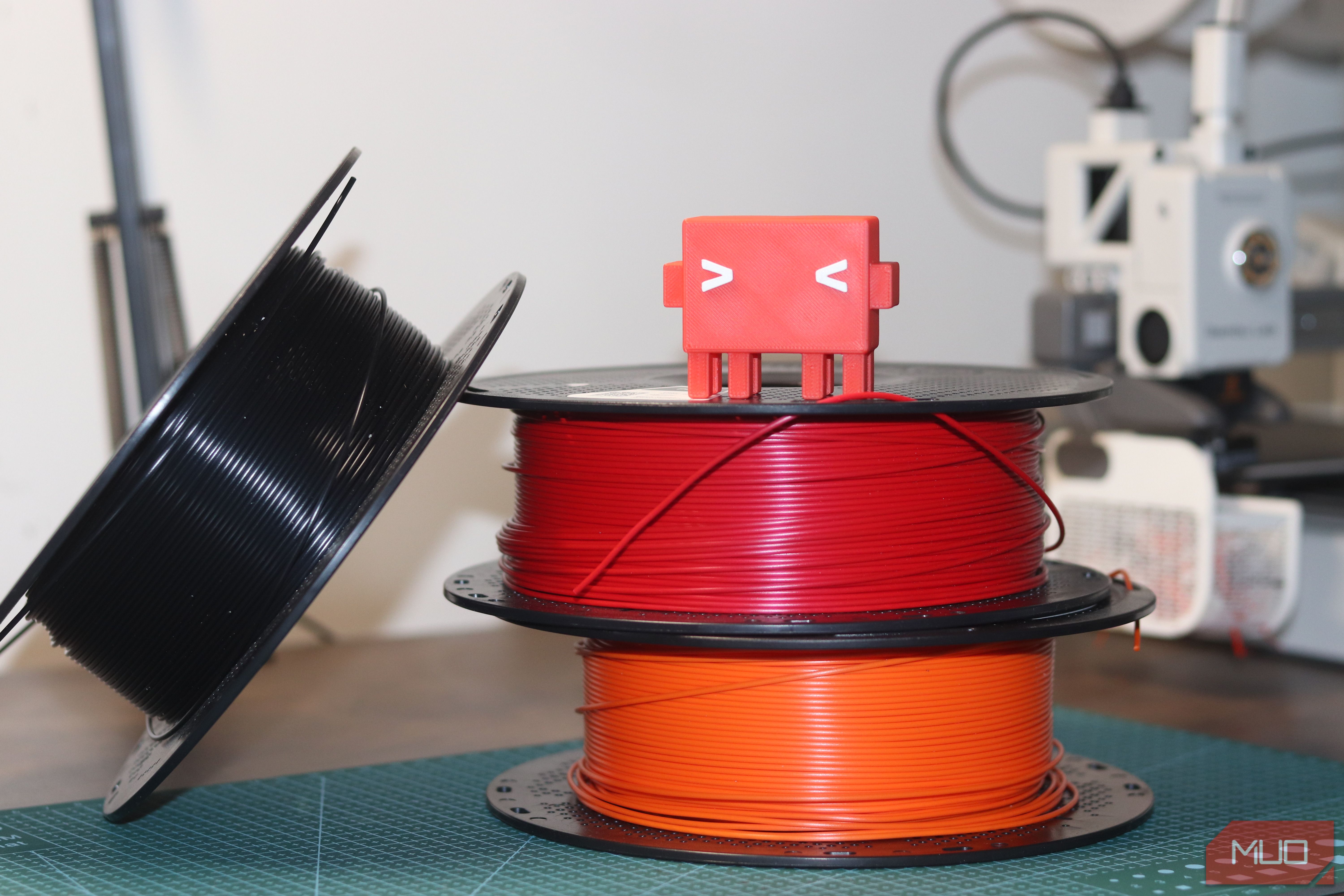Claude Code mascot on top of filament spools.