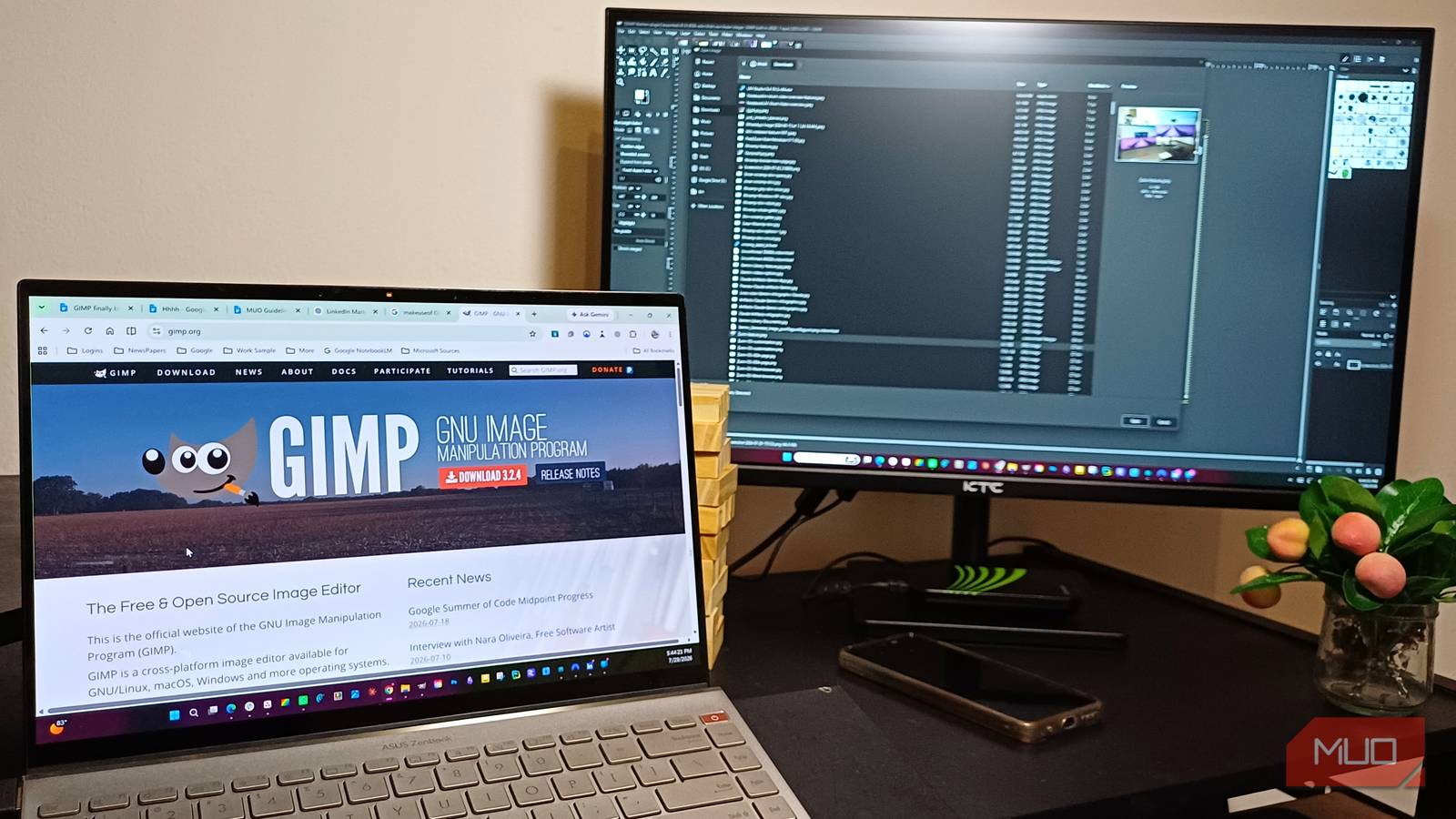 A laptop with GIMP download page on the screen with GIMP opene don a second monitor