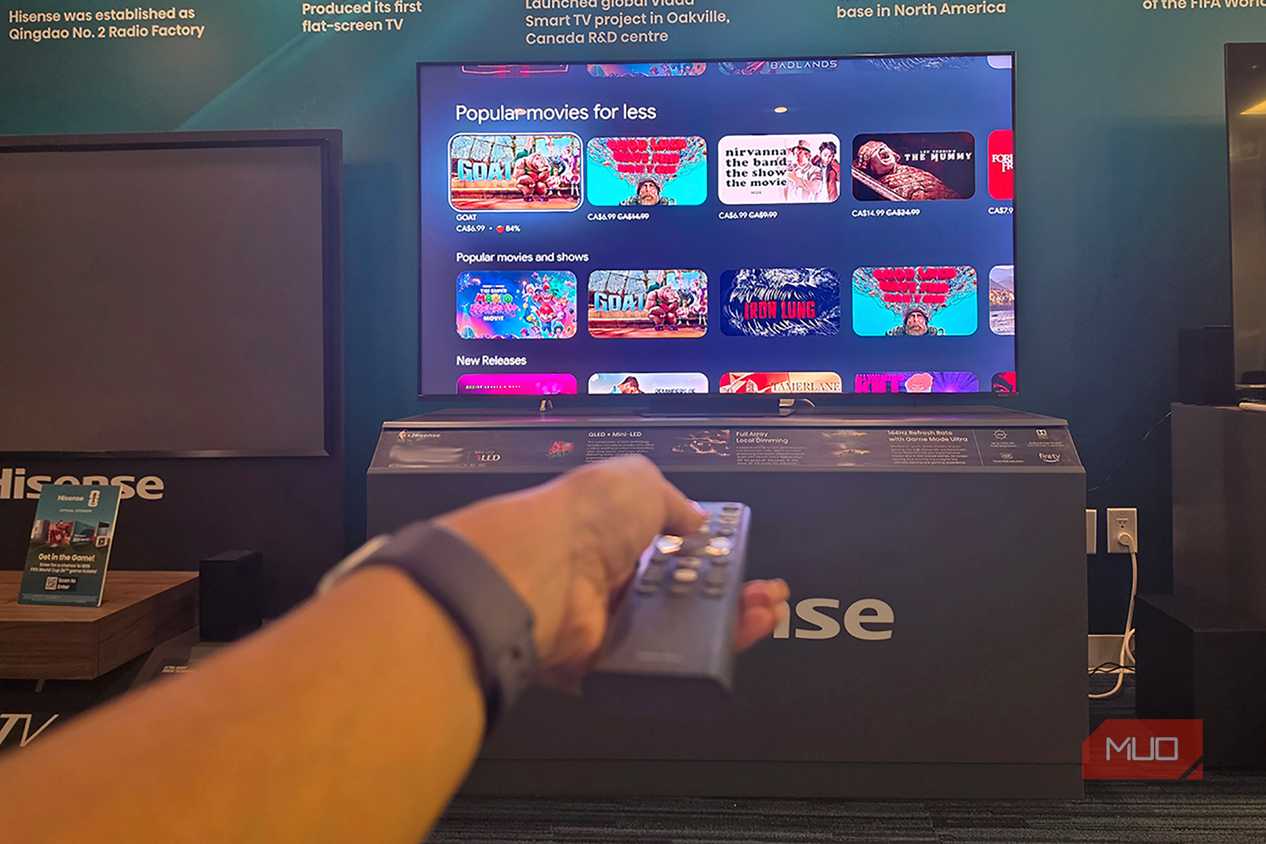 A hand holding a remote in front of a Hisense miniLED TV
