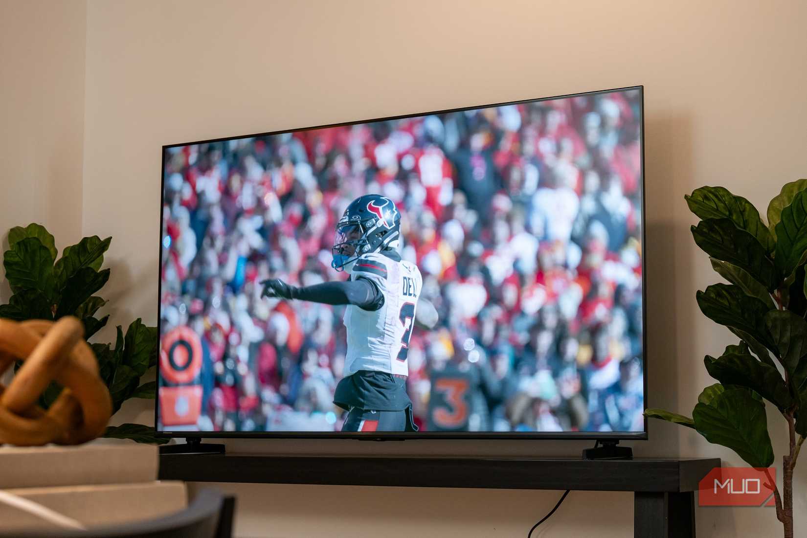 Hisense U6SF on dark console table displaying an NFL player in a Houston Texans uniform pointing at the camera in front of a stadium crowd.