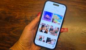 A hand holding an iPhone showing a Facebook photo album.