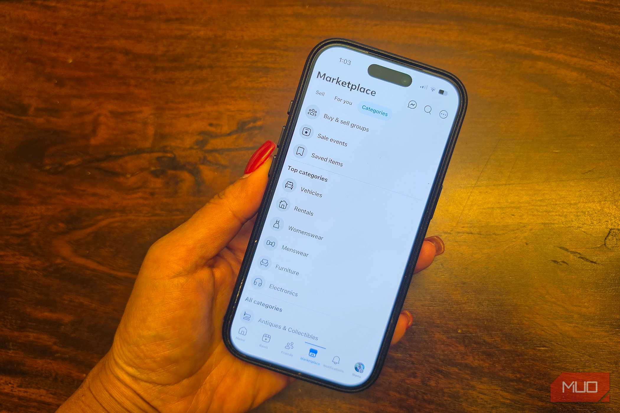 An iPhone in hand showing categories of items on Facebook Marketplace.