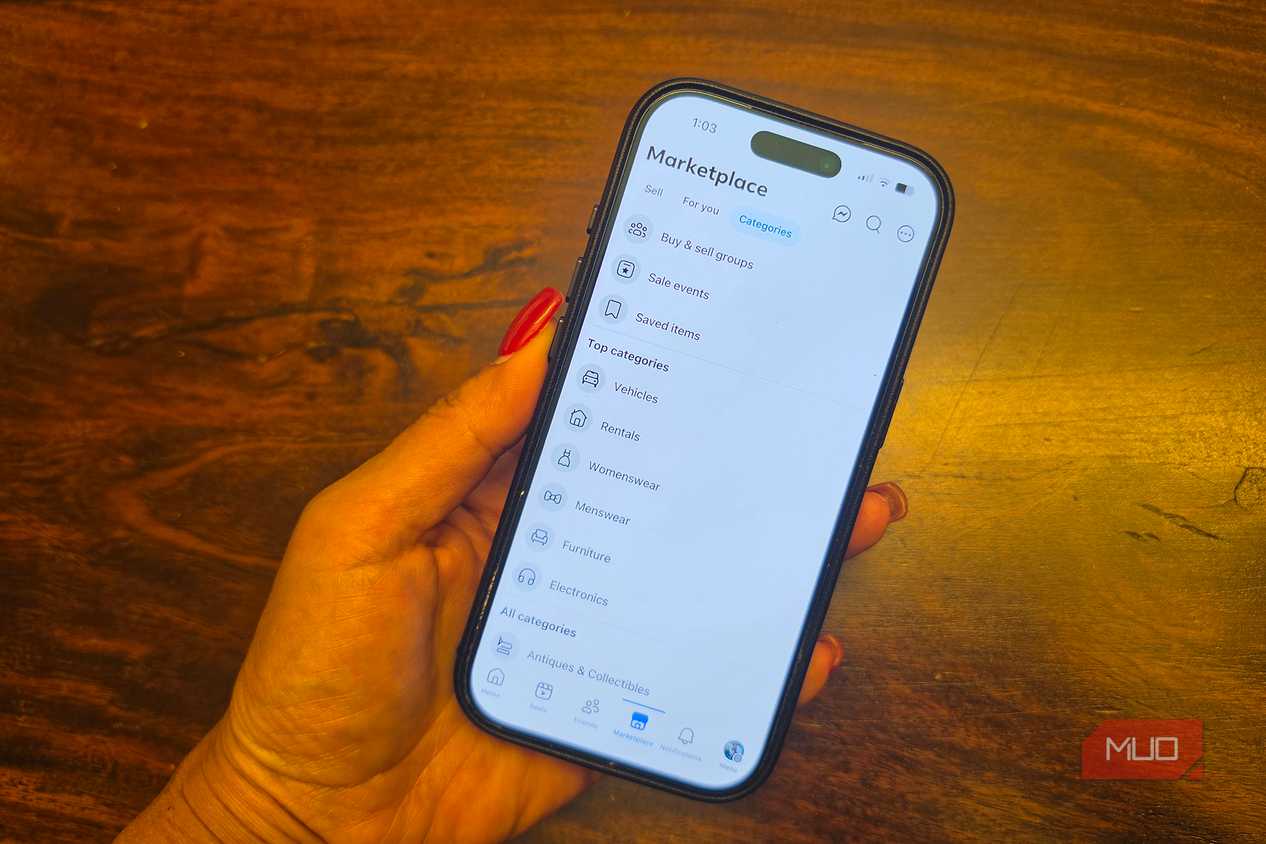 An iPhone in hand showing categories of items on Facebook Marketplace.