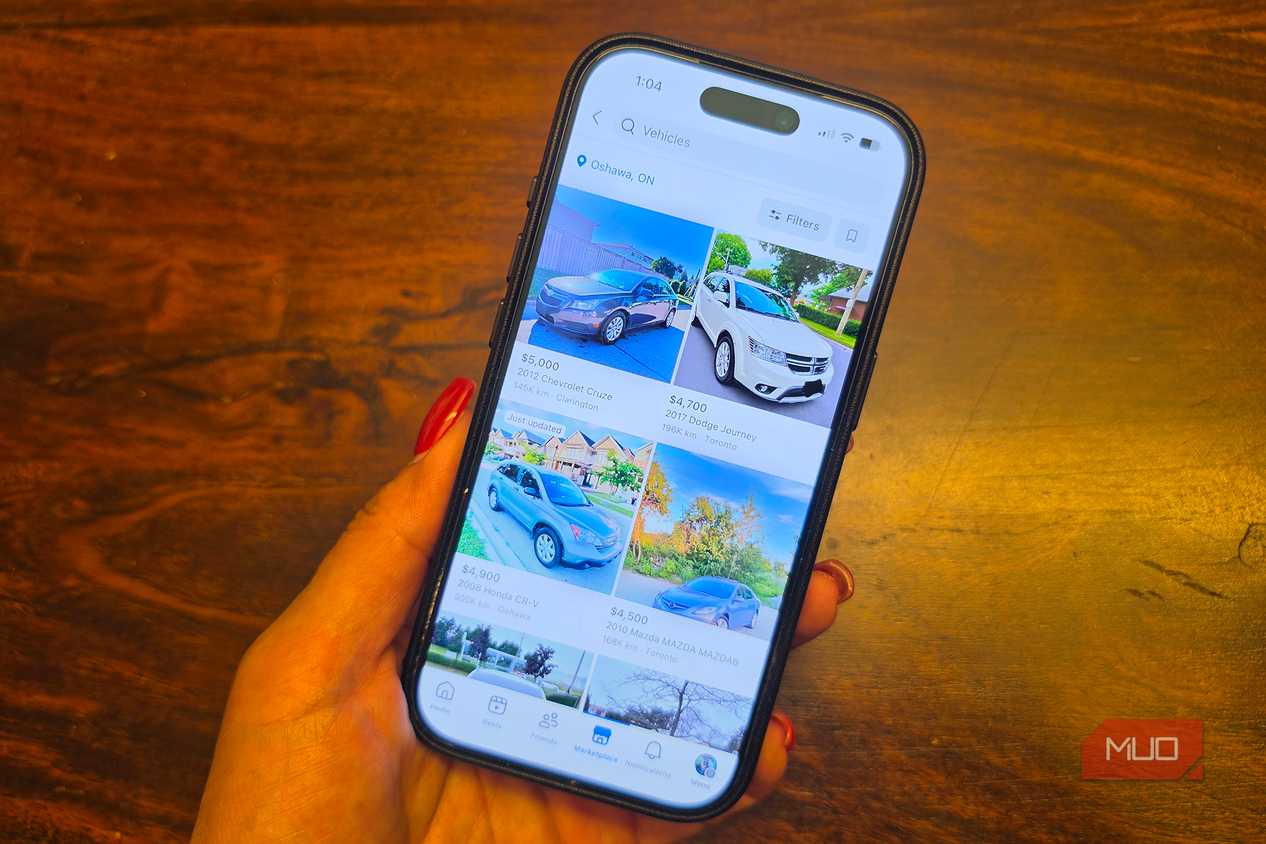 An iPhone in hand showing car listings on Facebook Marketplace.