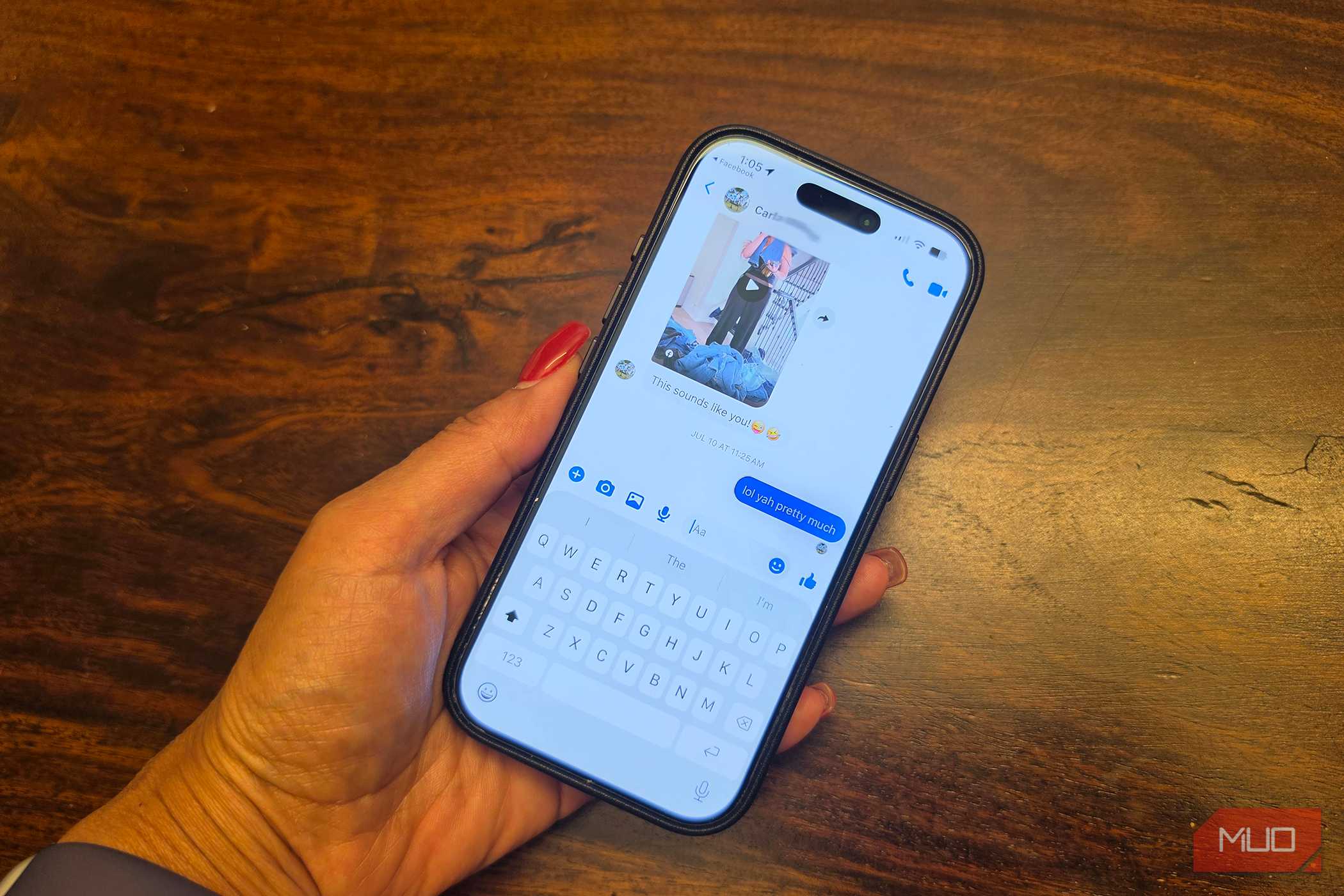 An iPhone in hand showing a Facebook Messenger conversation.