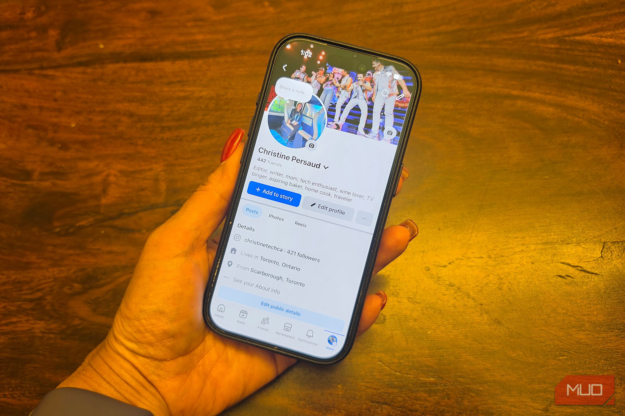 An iPhone in hand showing a Facebook profile.