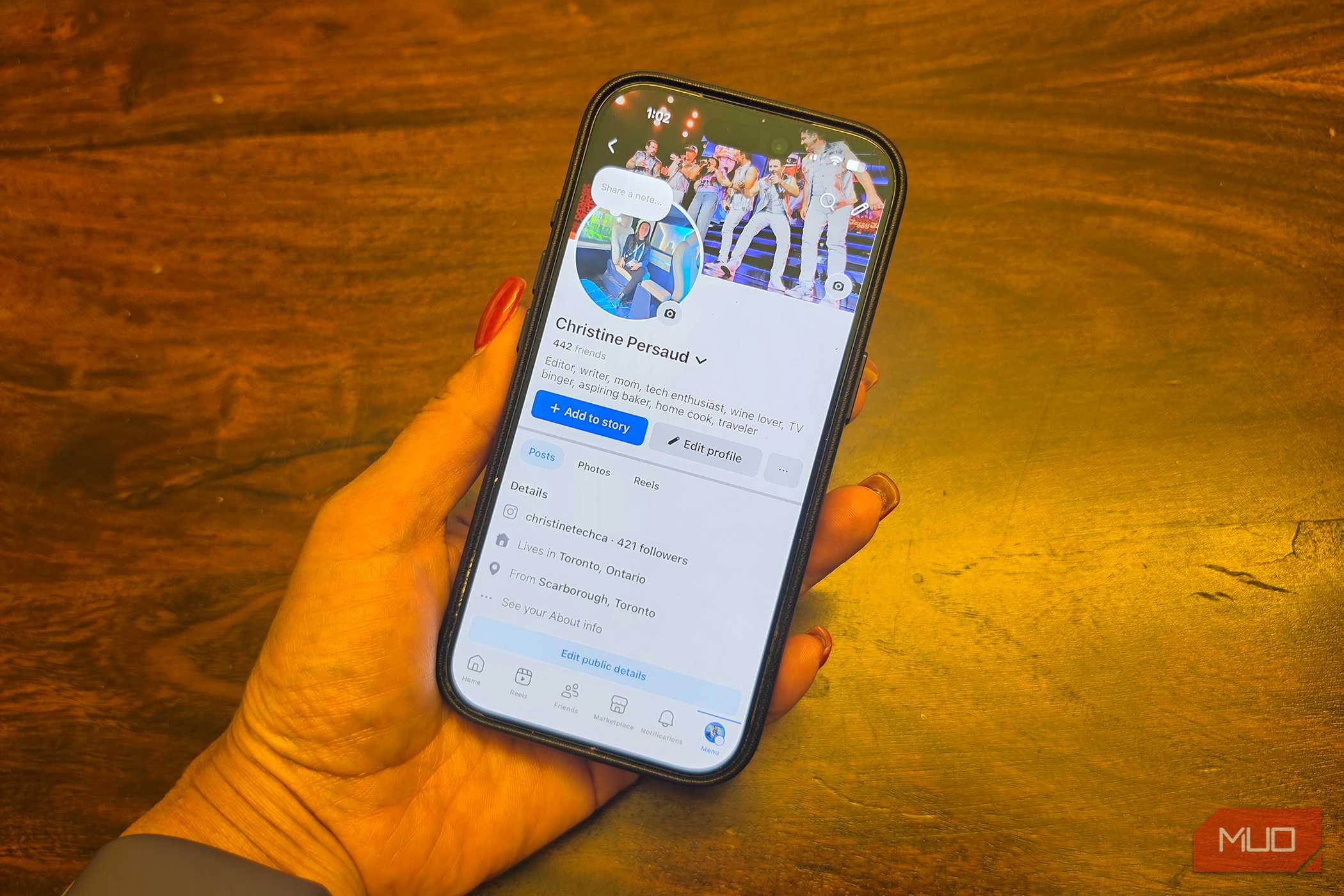An iPhone in hand showing a Facebook profile.