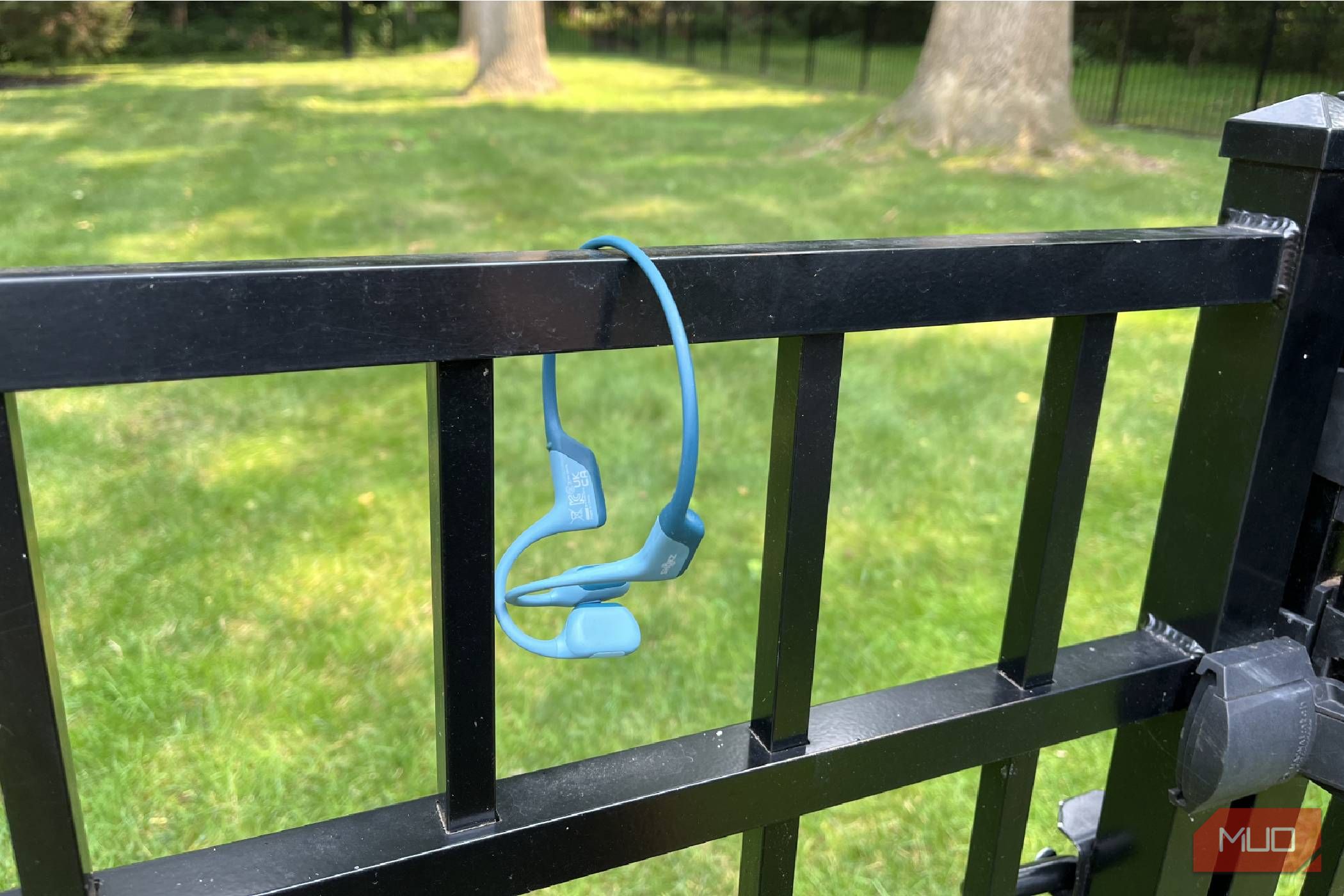 Shokz OpenRun Pro bone conduction headphones hanging on a gate.