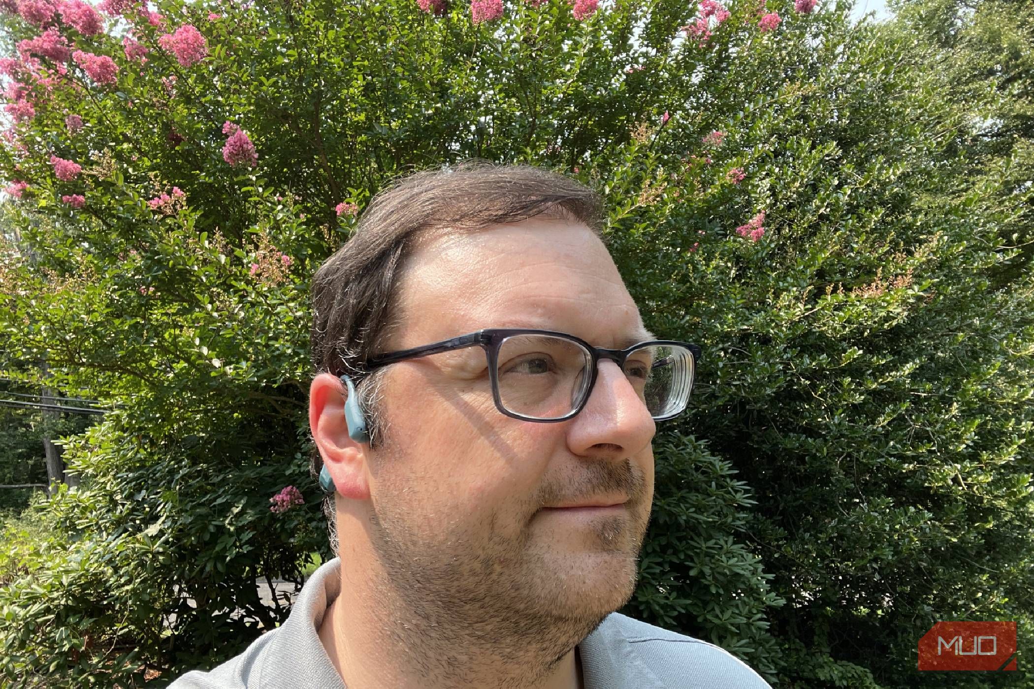 A man wearing Shokz OpenRun Pro bone conduction headphones in a yard.