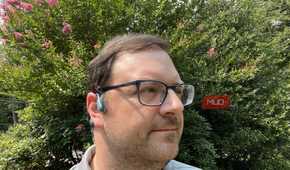 A man wearing Shokz OpenRun Pro bone conduction headphones in a yard.