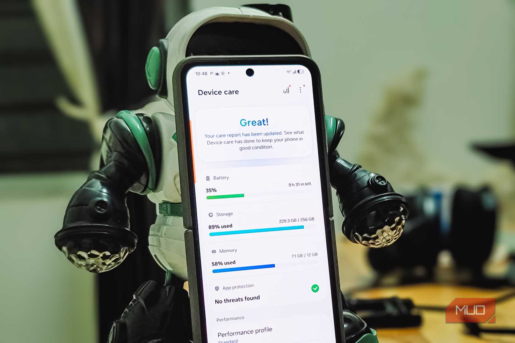 Samsung Galaxy Device Care screen held by robot figurine showing battery storage memory stats
