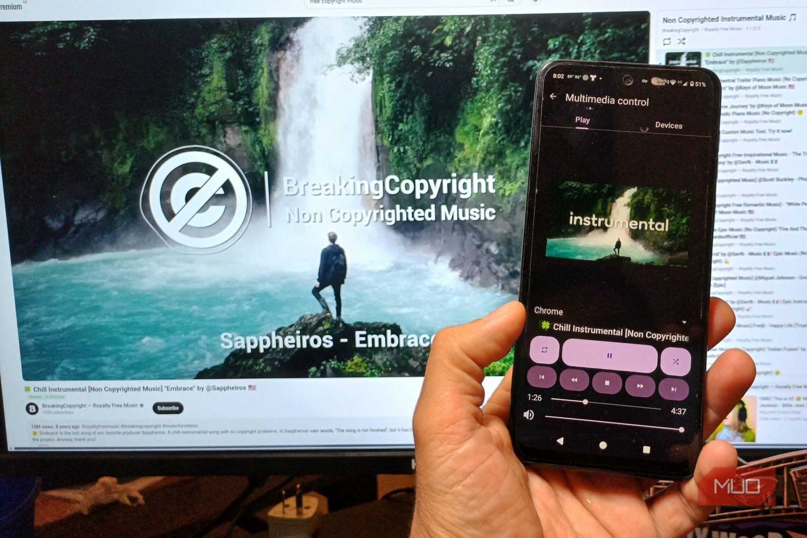 A hand holding an Android phone showing Zorin Connect media controls