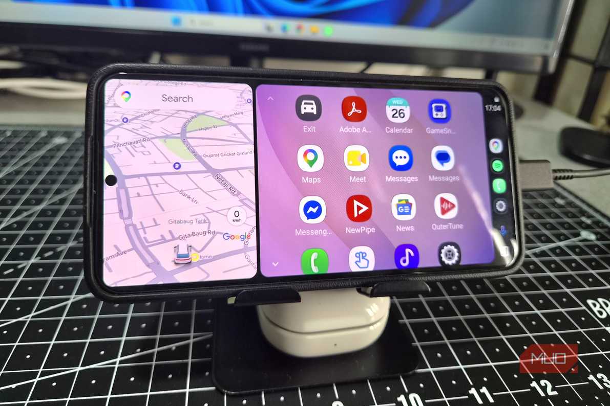 Компактное размещение смартфона на столе Смартфон на подставке под монитором с запущенным Android Auto