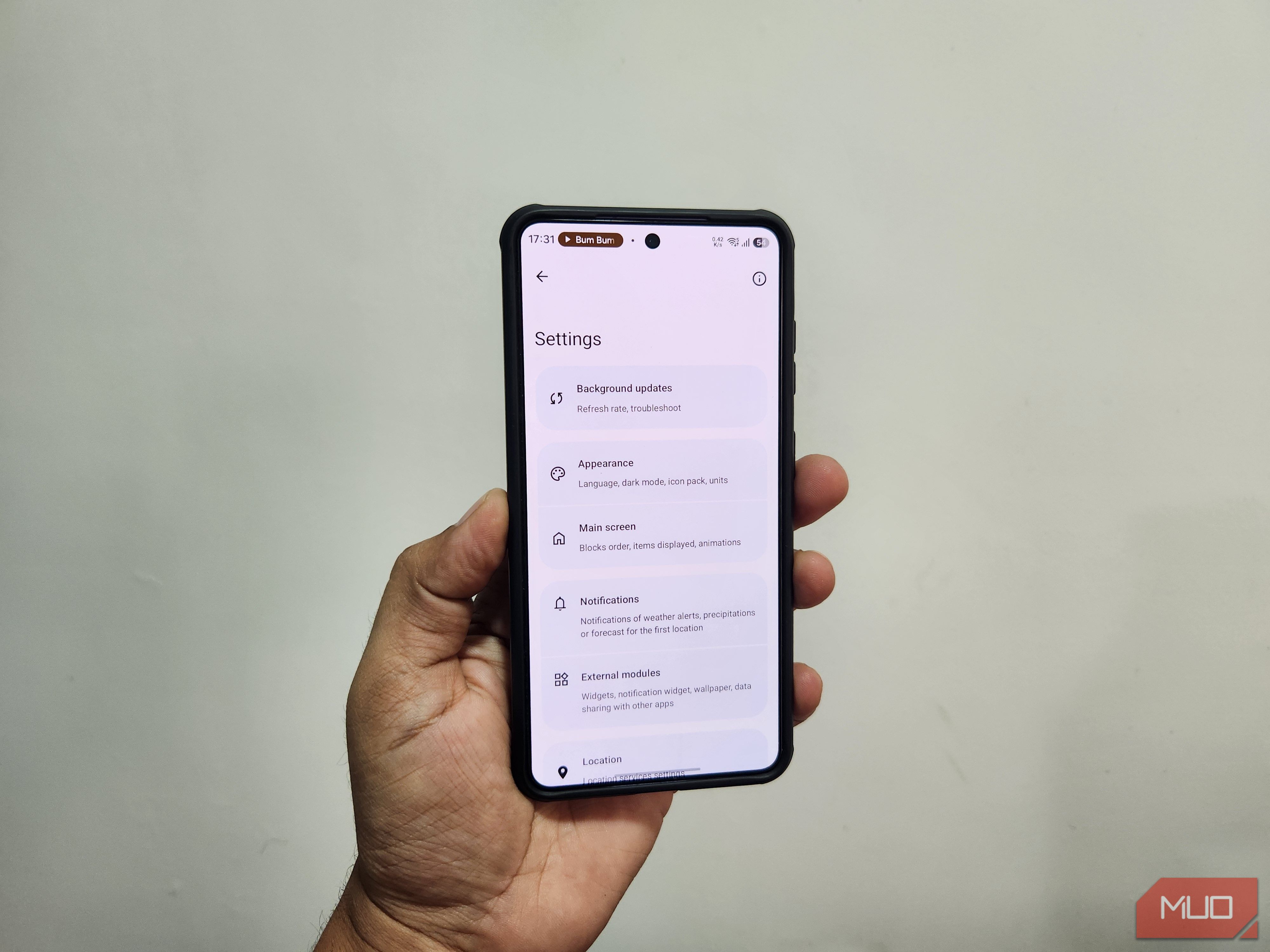 Android phone in hand showing Breezy Weather app