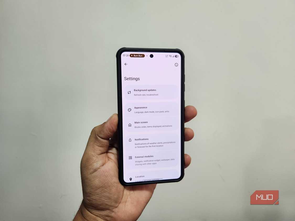 Android phone in hand showing Breezy Weather app